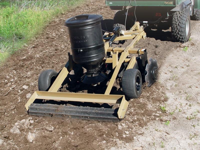 A black and tan land Pride FPS48 seeder being pulled behind a UTV across dirt